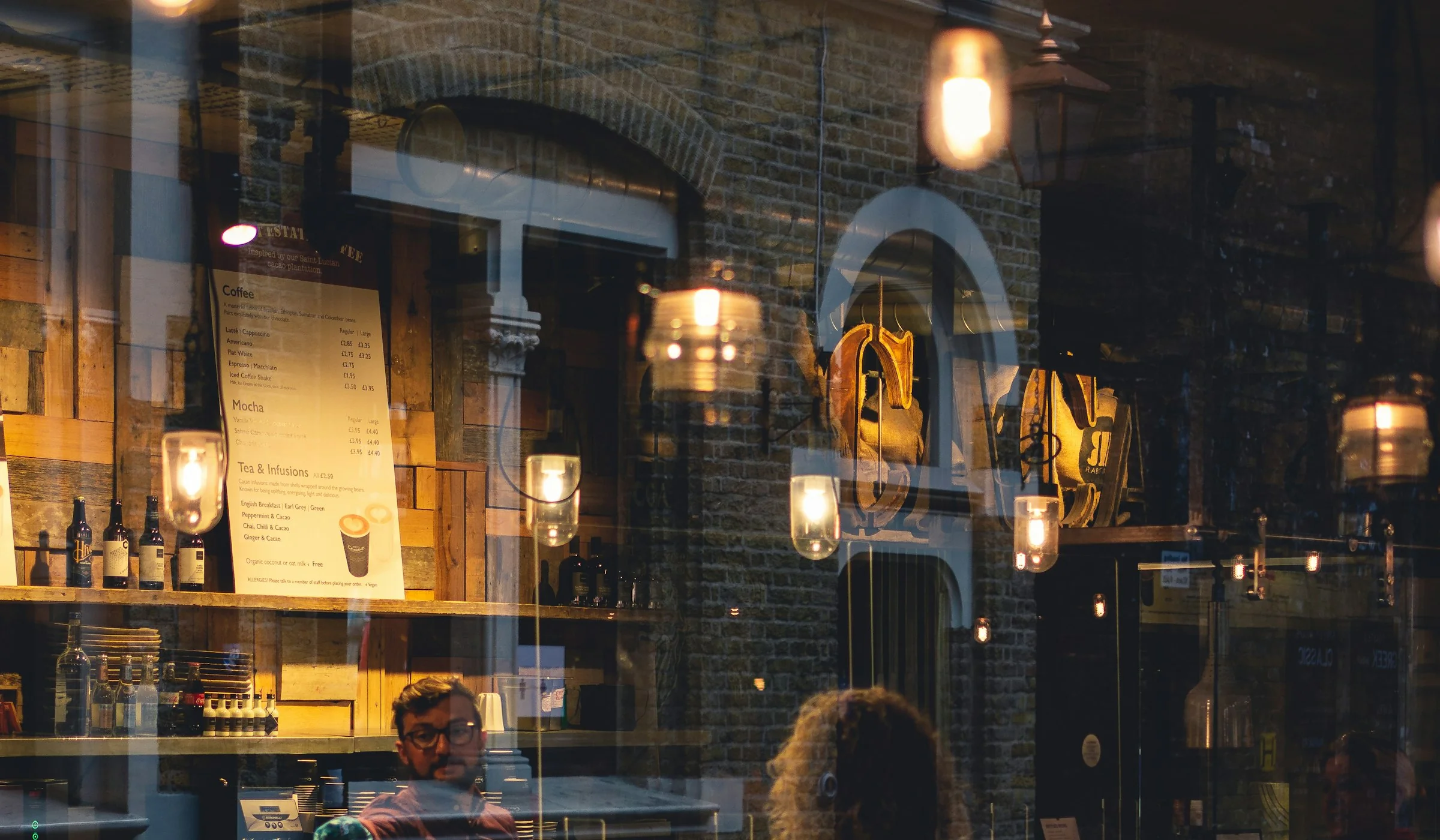 La salle d’un restaurant éclairée, vue de la rue à la nuit tombée